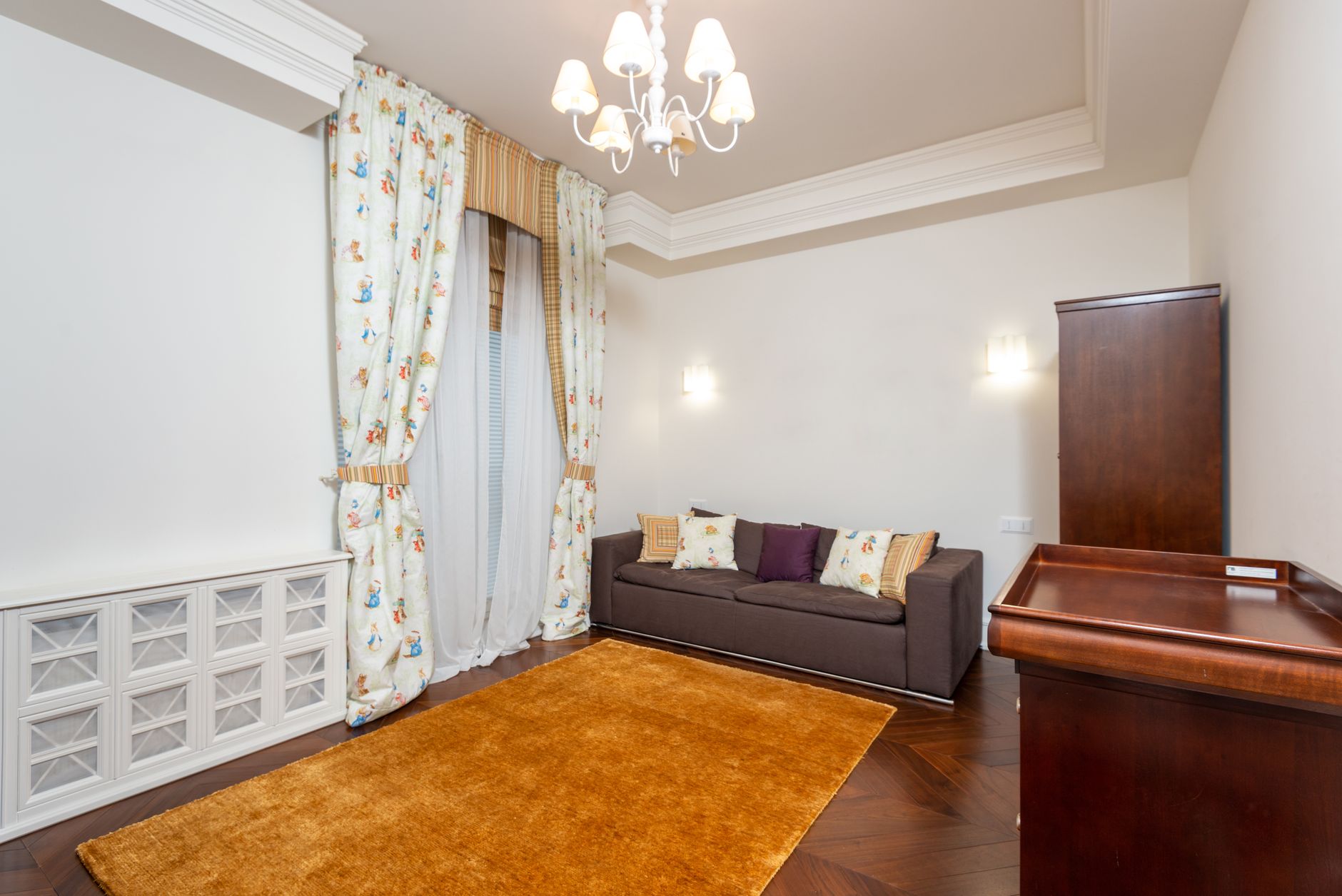 Bright and spacious living room featuring elegant chandelier, cozy sofa, and tasteful decor for a stylish ambiance